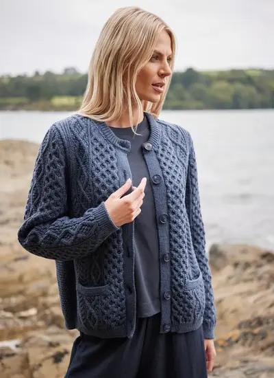 Ruby Aran Merino Lumber in Blue Melange Blonde Woman on Beach Wearing Aran Cardigan